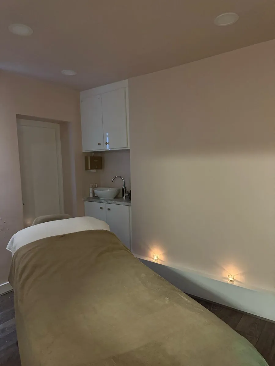 A candlelit treatment room at One Touch Wellness with a warm blanket over the massage couch